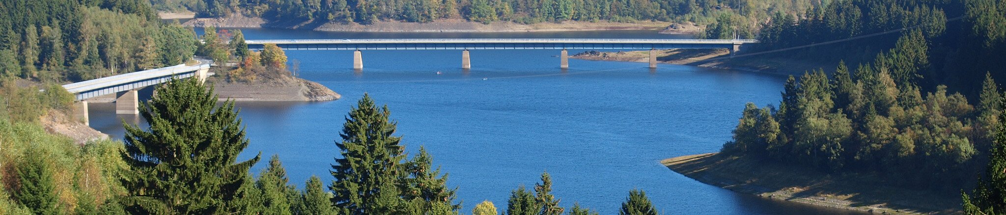 Landschaftsbild von einem See mit Brücke – ruhiges Wasser, über das sich eine malerische Brücke spannt, umgeben von grüner Natur und einer harmonischen Uferlandschaft.